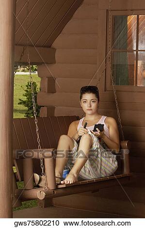 Portrait of a young woman sitting on a swing and holding a makeup brush View Large Photo Image Stock Image - Portrait of a young woman sitting on a swing and holding a makeup brush. Fotosearch