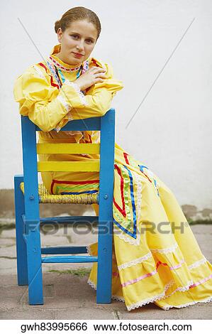 Stock Photograph - Portrait of a young woman sitting on a chair. Fotosearch