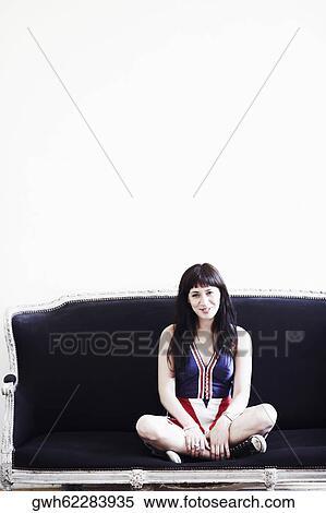 Portrait of a young woman sitting on a couch and smiling View Large Photo Image Stock Photography - Portrait of a young woman sitting on a couch and smiling. Fotosearch