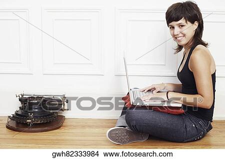Portrait of a young woman sitting on the floor and using a laptop View Large Photo Image Picture - Portrait of a young woman sitting on the floor and using a laptop. Fotosearch