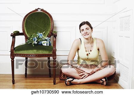 Portrait of a young woman sitting on the floor near an armchair View Large Photo Image Stock Image - Portrait of a young woman sitting on the floor near an armchair. Fotosearch