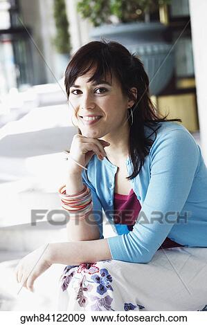 Portrait of a young woman sitting with her hand on her chin View Large Photo Image Stock Photo - Portrait of a young woman sitting with her hand on her chin . Fotosearch