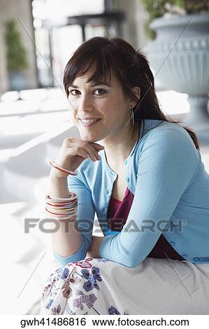 Portrait of a young woman sitting with her hand on her chin View Large Photo Image Stock Photograph - Portrait of a young woman sitting with her hand on her chin . Fotosearch