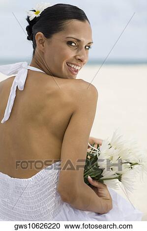 Portrait of a young woman smiling and holding flowers on the beach View Large Photo Image Stock Image - Portrait of a young woman smiling and holding flowers on the beach. Fotosearch