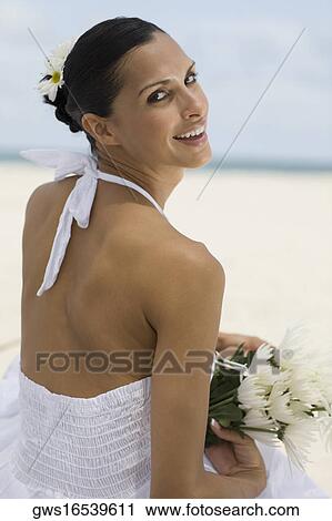 Portrait of a young woman smiling and holding flowers on the beach View Large Photo Image Stock Image - Portrait of a young woman smiling and holding flowers on the beach. Fotosearch