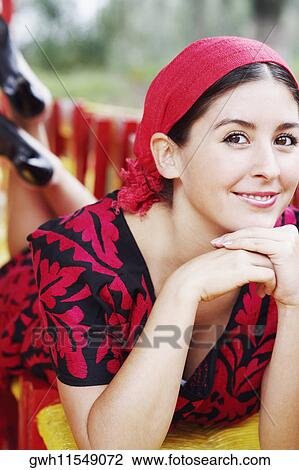 Stock Image - Portrait of a young woman smiling with her hand on her chin. Fotosearch