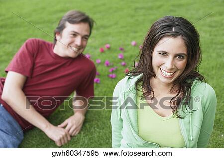 Portrait of a young woman smiling with a mid adult man lying on the grass View Large Photo Image Stock Photography - Portrait of a young woman smiling with a mid adult man lying on the grass. Fotosearch