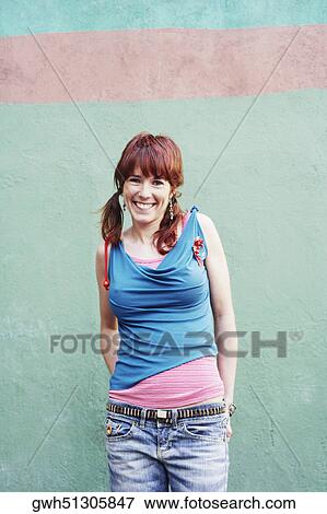 Portrait of a young woman standing in front of a wall and smiling View Large Photo Image Stock Photo - Portrait of a young woman standing in front of a wall and smiling. Fotosearch