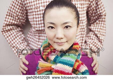 Stock Photograph - Portrait of a young woman standing in front of a man. Fotosearch