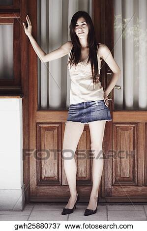Stock Photo - Portrait of a young woman standing with her hand on her waist. Fotosearch