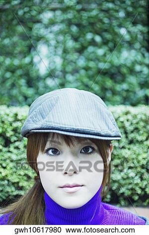Stock Image - Portrait of a young woman wearing a cap . Fotosearch