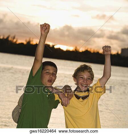 Picture - Portrait of two boys smiling with their hands raised. Fotosearch