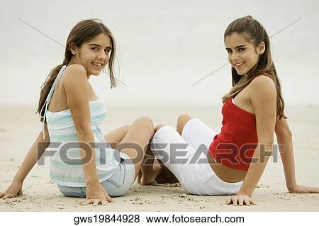 Stock Photo - Portrait of two girls sitting on the beach. Fotosearch
