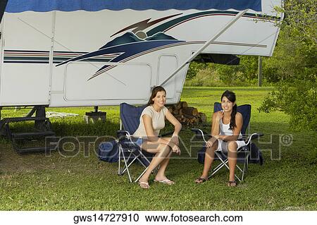 Stock Image - Portrait of two teenage girls sitting on armchairs. Fotosearch