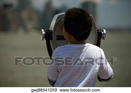 Stock Photo - Rear view of a boy looking through coin-operated binoculars, Manhattan, New York City, New York State, USA. Fotosearch