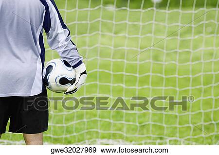 Stock Photo - Rear view of a goalie holding a soccer ball. Fotosearch