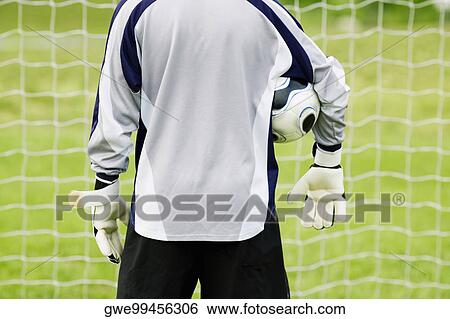 Rear view of a goalie with a soccer ball under his arm View Large Photo Image Stock Photograph - Rear view of a goalie with a soccer ball under his arm. Fotosearch
