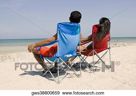 Rear view of a man and a woman sitting on the beach View Large Photo Image Stock Photo - Rear view of a man and a woman sitting on the beach. Fotosearch