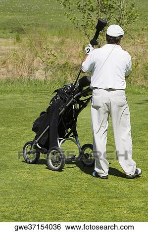 Stock Photograph - Rear view of a man taking out a golf club from a golf bag. Fotosearch
