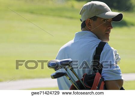 Rear view of a mature man carrying a golf bag View Large Photo Image Stock Photo - Rear view of a mature man carrying a golf bag. Fotosearch