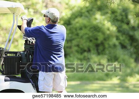 Stock Photography - Rear view of a mature man picking a golf club from a golf bag. Fotosearch