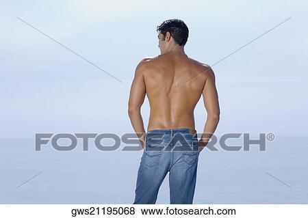 Rear view of a mid adult man standing on the beach View Large Photo Image Stock Photo - Rear view of a mid adult man standing on the beach. Fotosearch