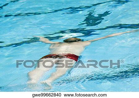 Rear view of a mid adult man swimming in a swimming pool View Large Photo Image Stock Image - Rear view of a mid adult man swimming in a swimming pool. Fotosearch