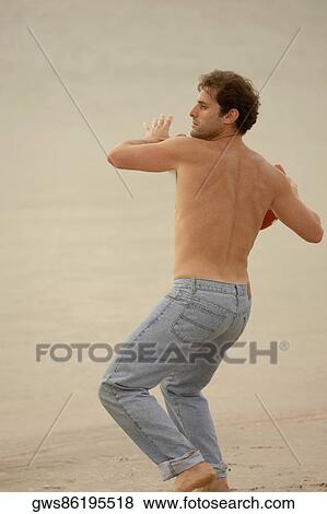 Rear view of a mid adult man throwing a rugby ball on the beach View Large Photo Image Stock Photo - Rear view of a mid adult man throwing a rugby ball on the beach. Fotosearch