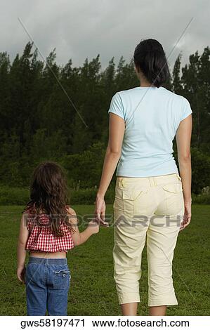 Stock Image - Rear view of a mother holding her daughter's hand. Fotosearch