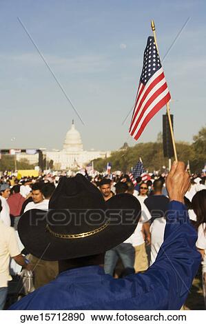 Stock Image - Rear view of a person holding an American flag in front of a government building, California State Capitol Building, California, USA. Fotosearch