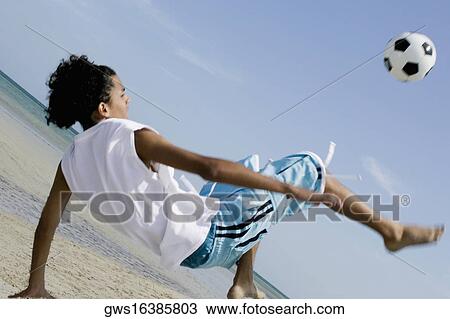 Rear view of a teenage boy playing with a soccer ball on the beach View Large Photo Image Stock Image - Rear view of a teenage boy playing with a soccer ball on the beach. Fotosearch