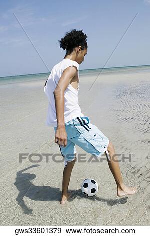 Stock Photo - Rear view of a teenage girl playing with a soccer ball on the beach. Fotosearch