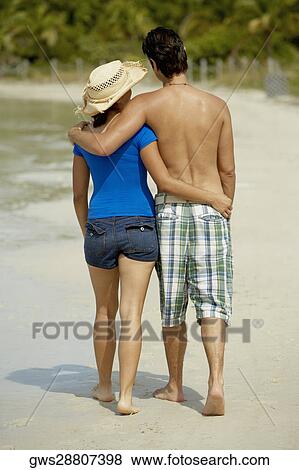 Rear view of a teenage girl walking on the beach with her arm around a young man View Large Photo Image Stock Photo - Rear view of a teenage girl walking on the beach with her arm around a young man. Fotosearch