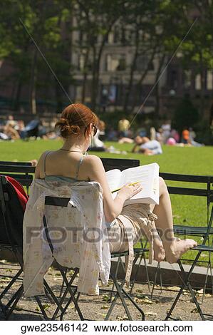 Rear view of a woman sitting on a chair and reading a book View Large Photo Image Stock Image - Rear view of a woman sitting on a chair and reading a book. Fotosearch