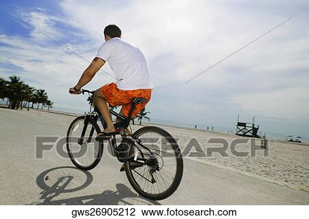 Rear view of a young man cycling View Large Photo Image Stock Image - Rear view of a young man cycling. Fotosearch