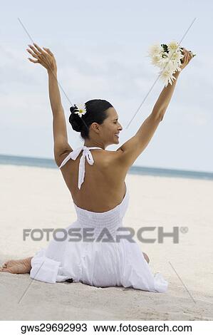 Rear view of a young woman holding flowers on the beach View Large Photo Image Stock Image - Rear view of a young woman holding flowers on the beach. Fotosearch