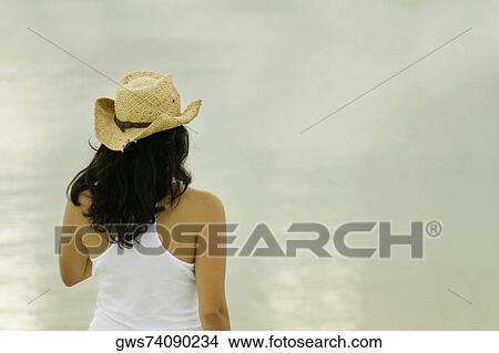 Picture - Rear view of a young woman wearing a sun hat. Fotosearch