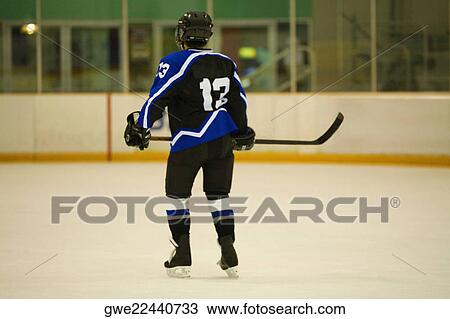 Stock Image - Rear view of an ice hockey player playing ice hockey. Fotosearch