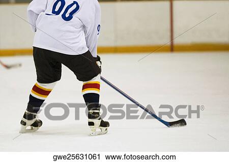 Stock Image - Rear view of an ice hockey player playing ice hockey. Fotosearch