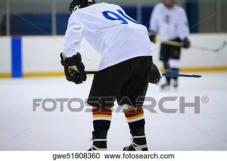 Stock Image - Rear view of an ice hockey player playing ice hockey. Fotosearch