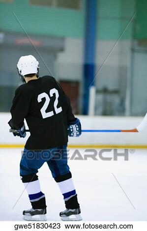 Stock Image - Rear view of an ice hockey player playing ice hockey. Fotosearch