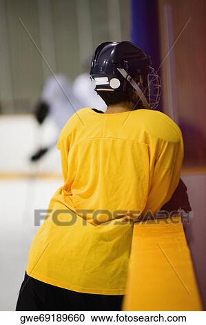 Rear view of an ice hockey player leaning on a railing View Large Photo Image Stock Image - Rear view of an ice hockey player leaning on a railing. Fotosearch