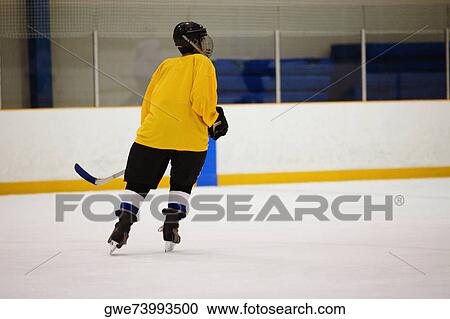 Stock Image - Rear view of an ice hockey player playing ice hockey. Fotosearch