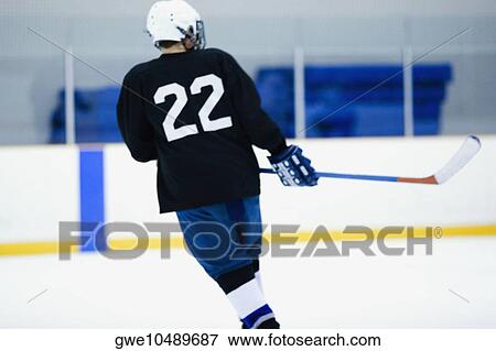 Stock Photo - Rear view of an ice hockey player playing ice hockey. Fotosearch
