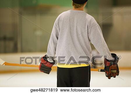 Rear view of an ice hockey player holding an ice hockey stick View Large Photo Image Stock Photo - Rear view of an ice hockey player holding an ice hockey stick. Fotosearch