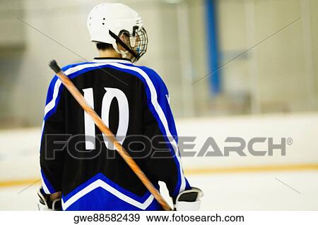 Stock Photo - Rear view of an ice hockey player holding an ice hockey stick. Fotosearch