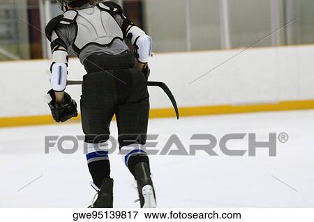 Stock Photo - Rear view of an ice hockey player playing ice hockey. Fotosearch