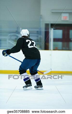 Rear view of an ice hockey player playing ice hockey View Large Photo Image Stock Photography - Rear view of an ice hockey player playing ice hockey. Fotosearch