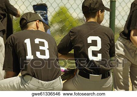 Rear view of two baseball players sitting on a bench View Large Photo Image Stock Photograph - Rear view of two baseball players sitting on a bench. Fotosearch