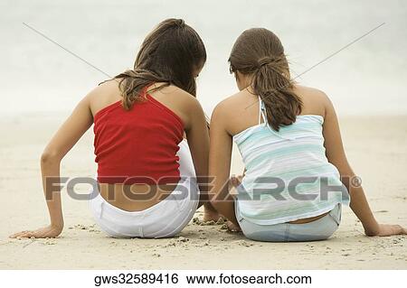 Rear view of two girls sitting on the beach View Large Photo Image Stock Photograph - Rear view of two girls sitting on the beach. Fotosearch